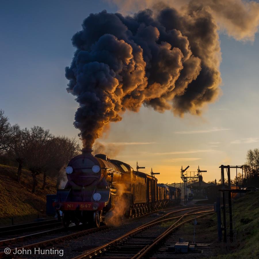 The Departing Goods Train Catches the Last Rays of the Sun by John Hunting